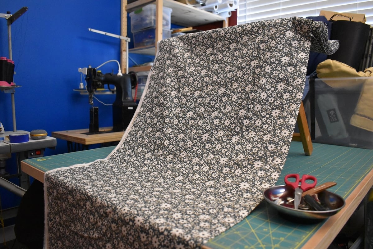 Blue-green fabric with a small floral motif draped over a stool.