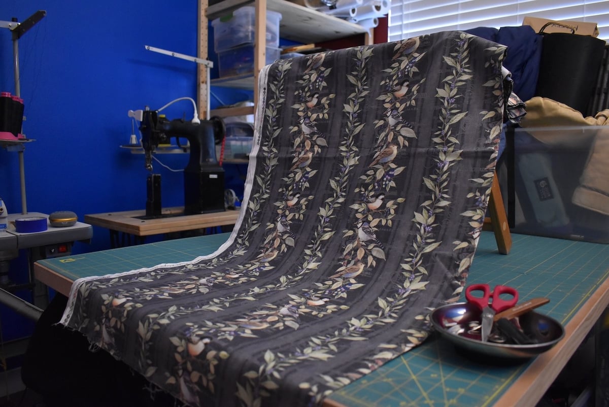 Medium gray fabric with a bird motif draped over a stool.