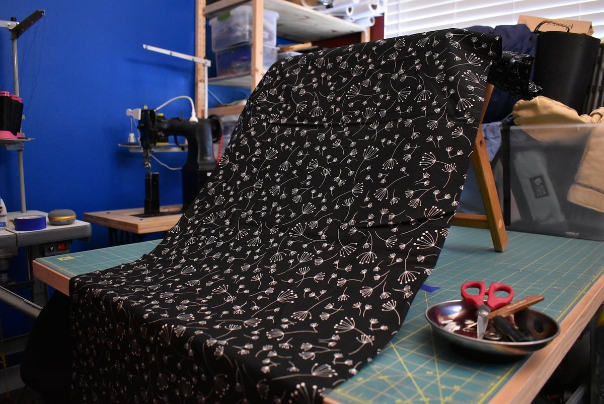 Black fabric with a small white floral motif draped over a stool.