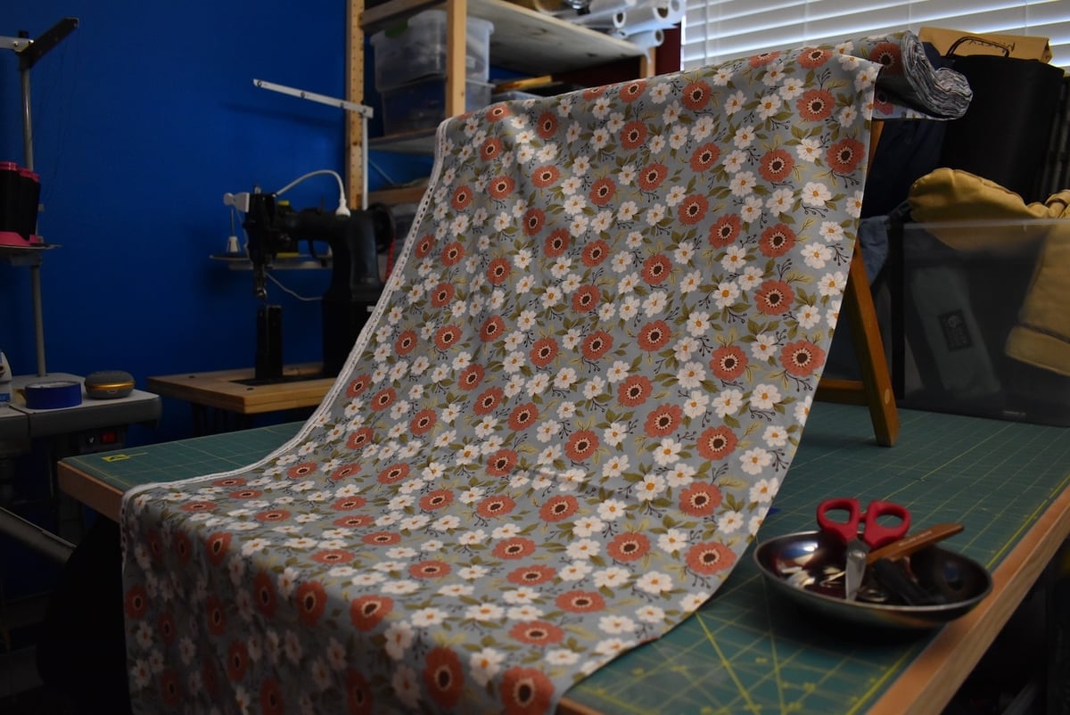 Light gray fabric with a medium-size floral motif draped over a stool.