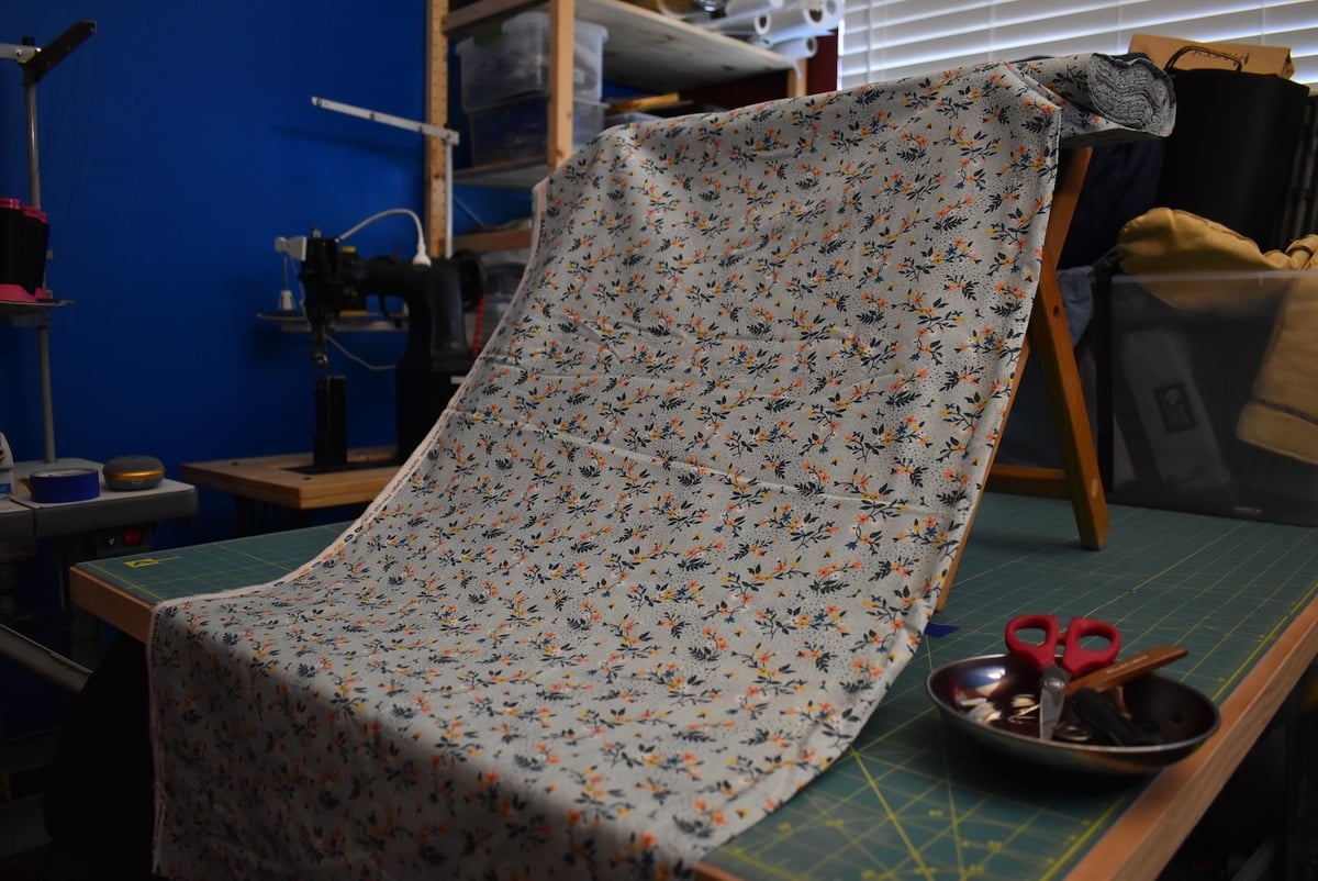 Light blue fabric with a small floral motif draped over a stool.