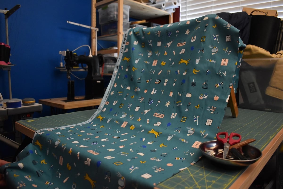 Teal fabric with assorted whatnot motif draped over a stool.