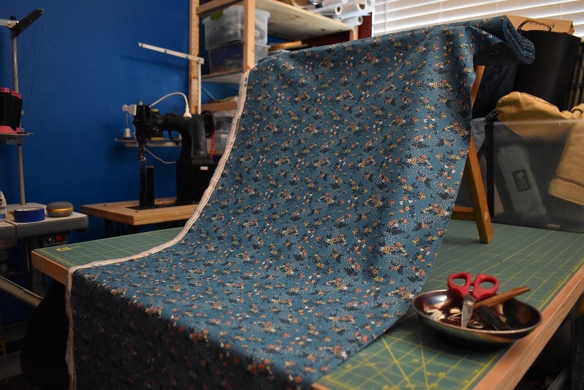 Teal fabric with a floral motif draped over a stool.