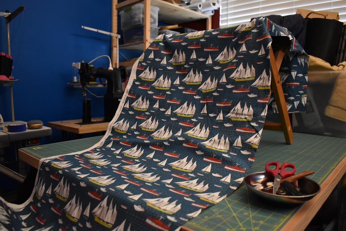 Dark blue fabric with a sailboat motif draped over a stool.