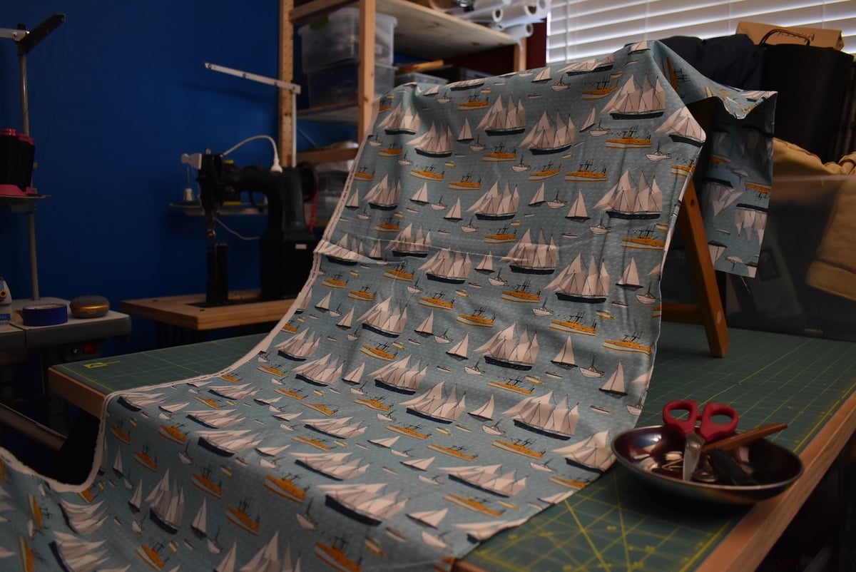 Light blue fabric with a sailboat motif draped over a stool.