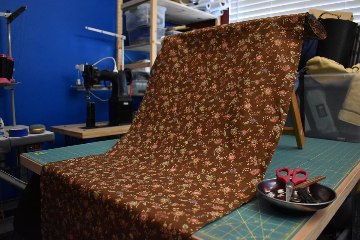 Brown fabric with a small floral motif draped over a stool.