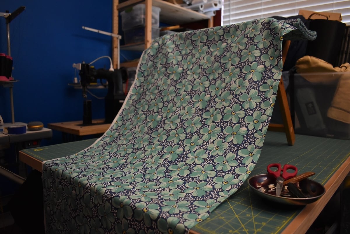 Blue fabric with a medium floral motif draped over a stool.