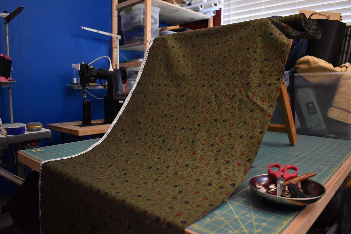 Green fabric with a small floral motif draped over a stool