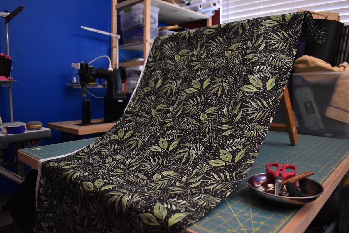 Dark fabric with leaf patterns draped over a stool.