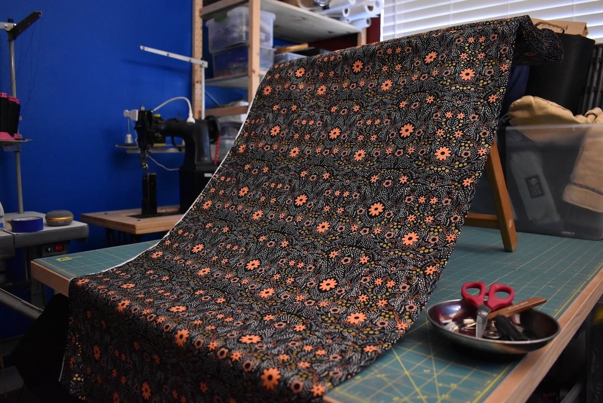 Dark fabric with a multicolored flower motif draped over a stool.