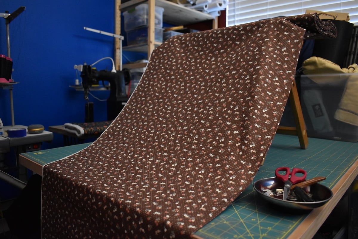 Brown fabric with a small floral motif draped over a stool.