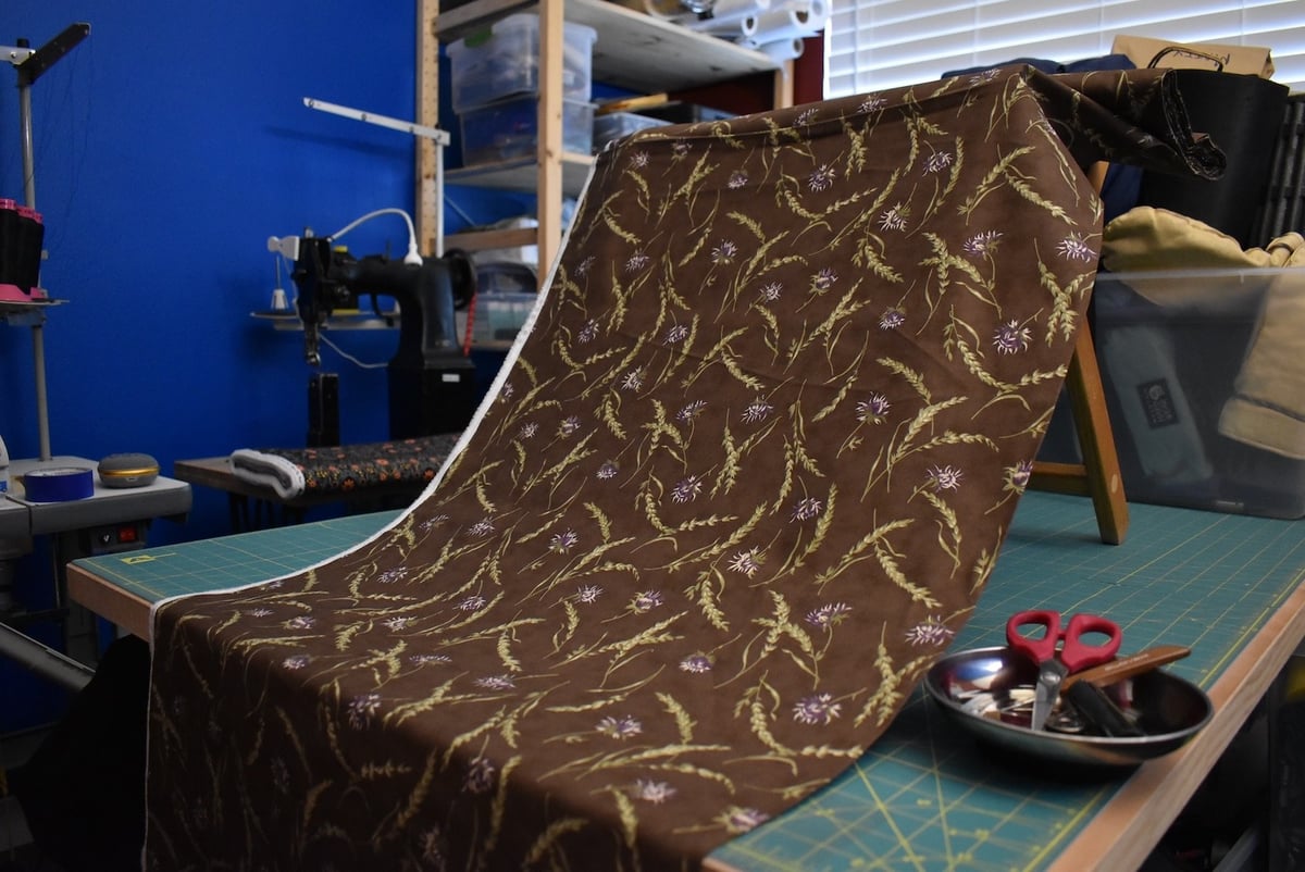 Brown fabric with a thistle motif draped over a stool