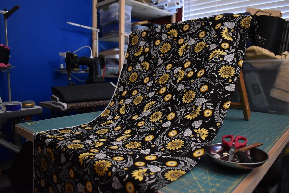 Dark fabric with a bee and flower motif draped over a stool.