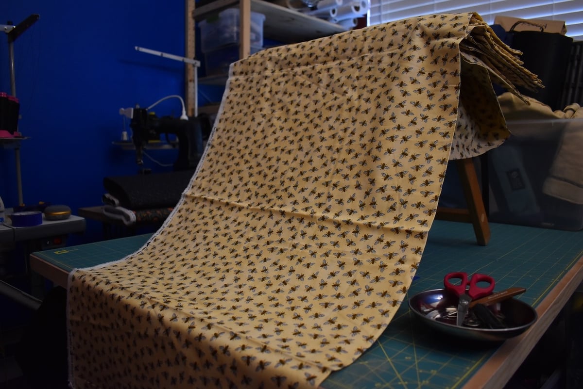 Yellow fabric with a honeybee motif draped over a stool.