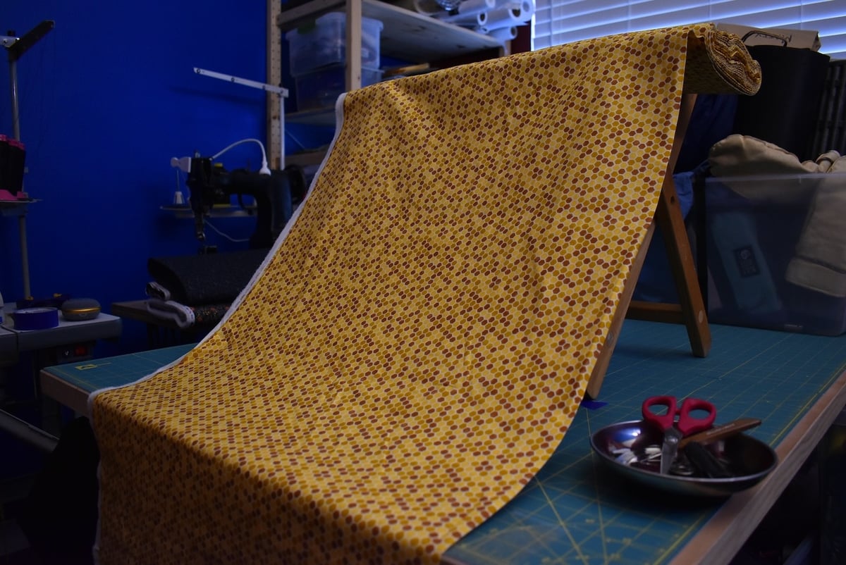 Yellow fabric with a hexagonal/honeycomb motif draped over a stool