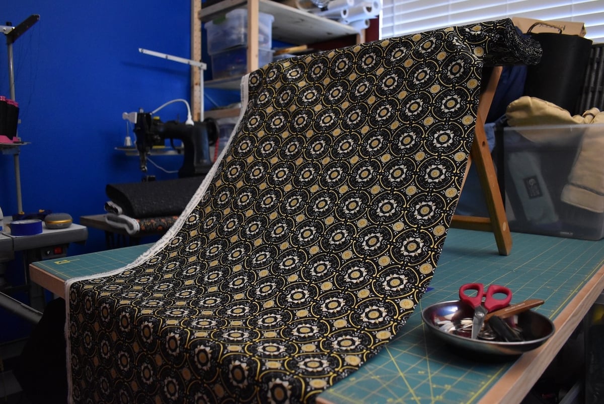 Dark fabric with a geometric bee motif draped over a stool.