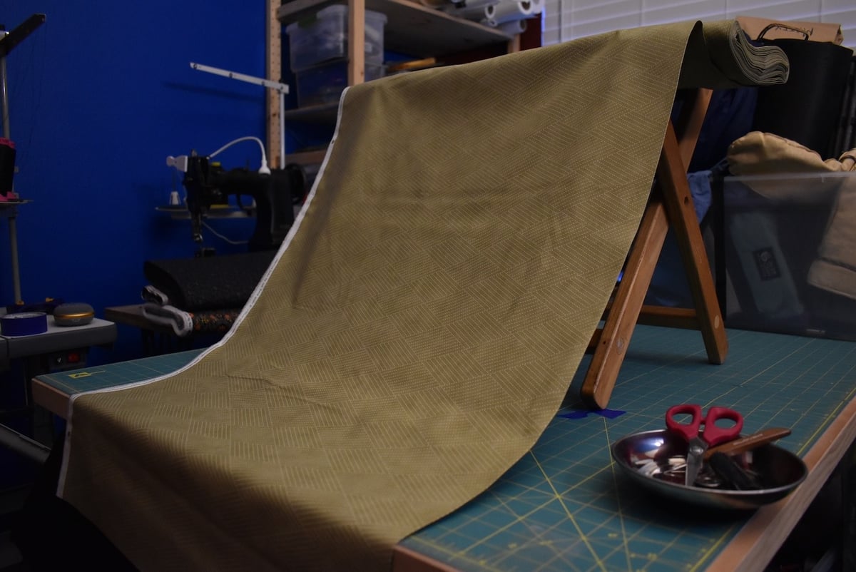 Green fabric with a linear pattern draped over a stool.