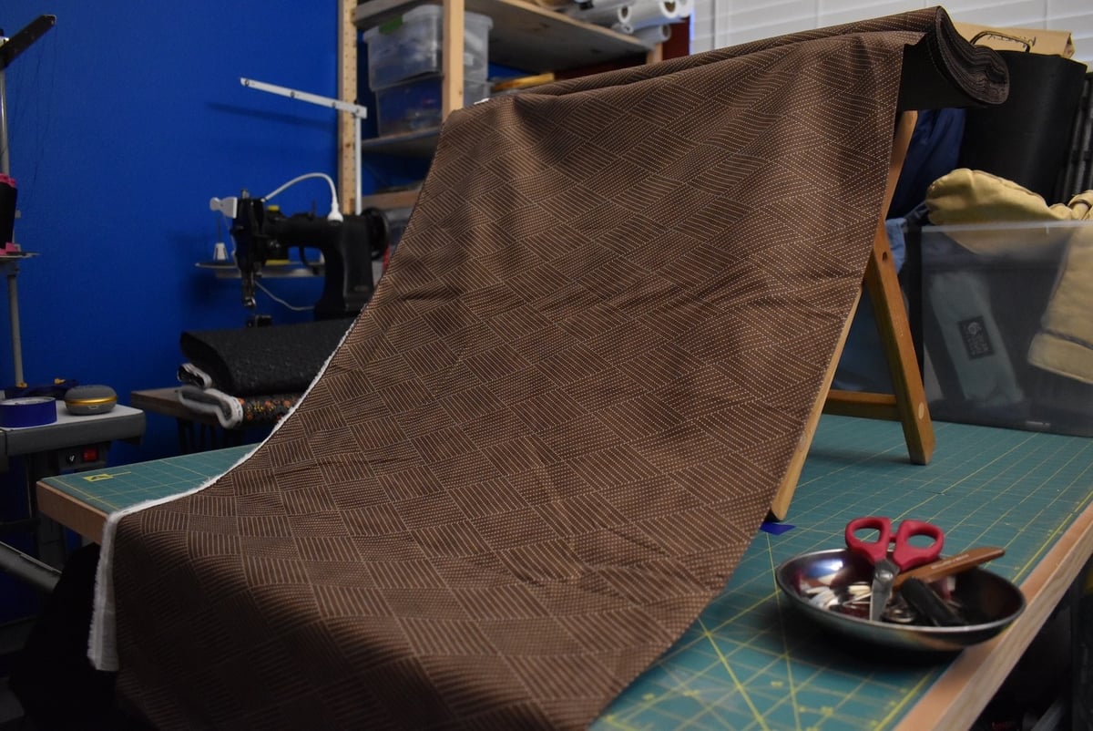 Brown fabric with a linear motif draped over a stool.