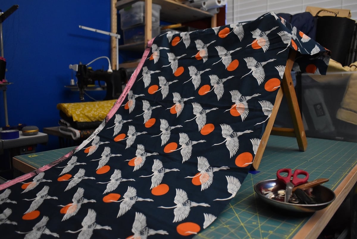 Navy fabric with a flying crane motif draped over a stool.