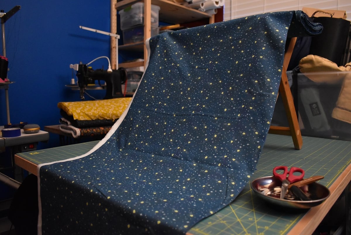 Dark blue fabric with a firefly motif draped over a stool.