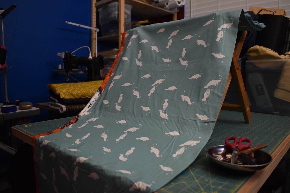 Teal fabric with manatee motif draped over a stool.