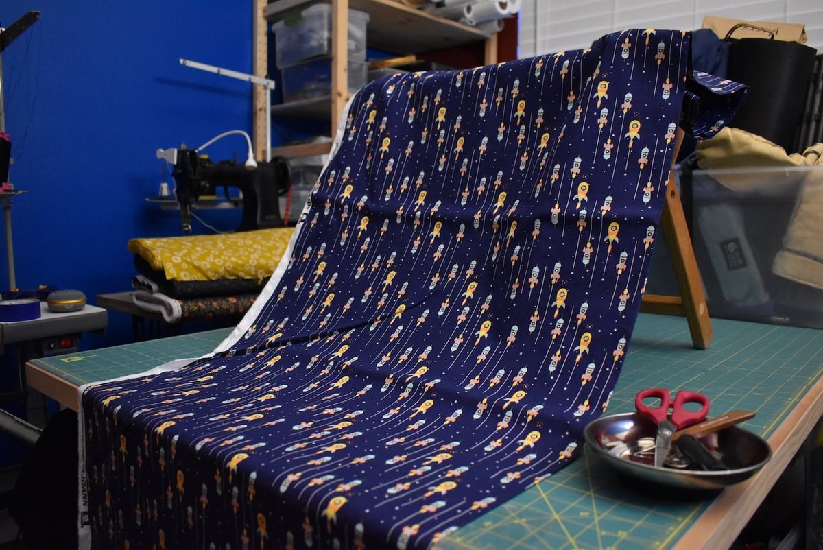 Navy fabric with a rocketship motif draped over a stool.