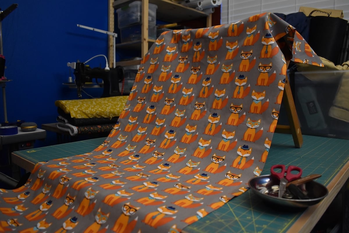 Gray fabric with well-dressed orange foxes draped over a stool.