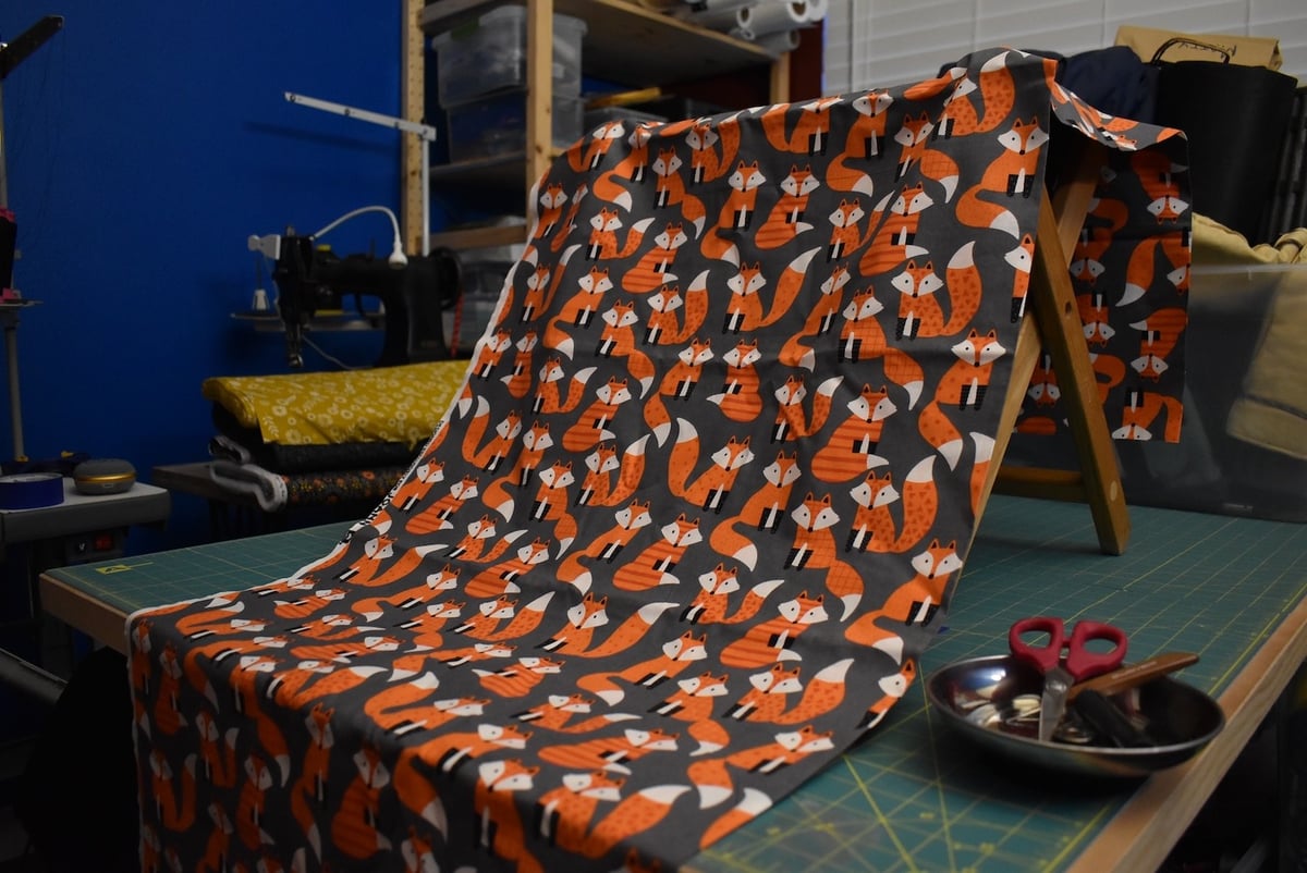 Gray fabric with an orange fox motif draped over a stool.